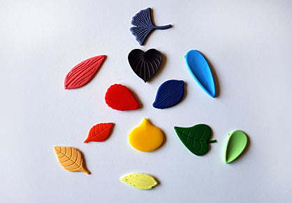 Several clay leaves in a variety of colors laid around in a circle