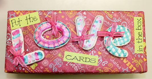 Pink and turquoise decorated love letters with ribbons on a pink patterned gift box